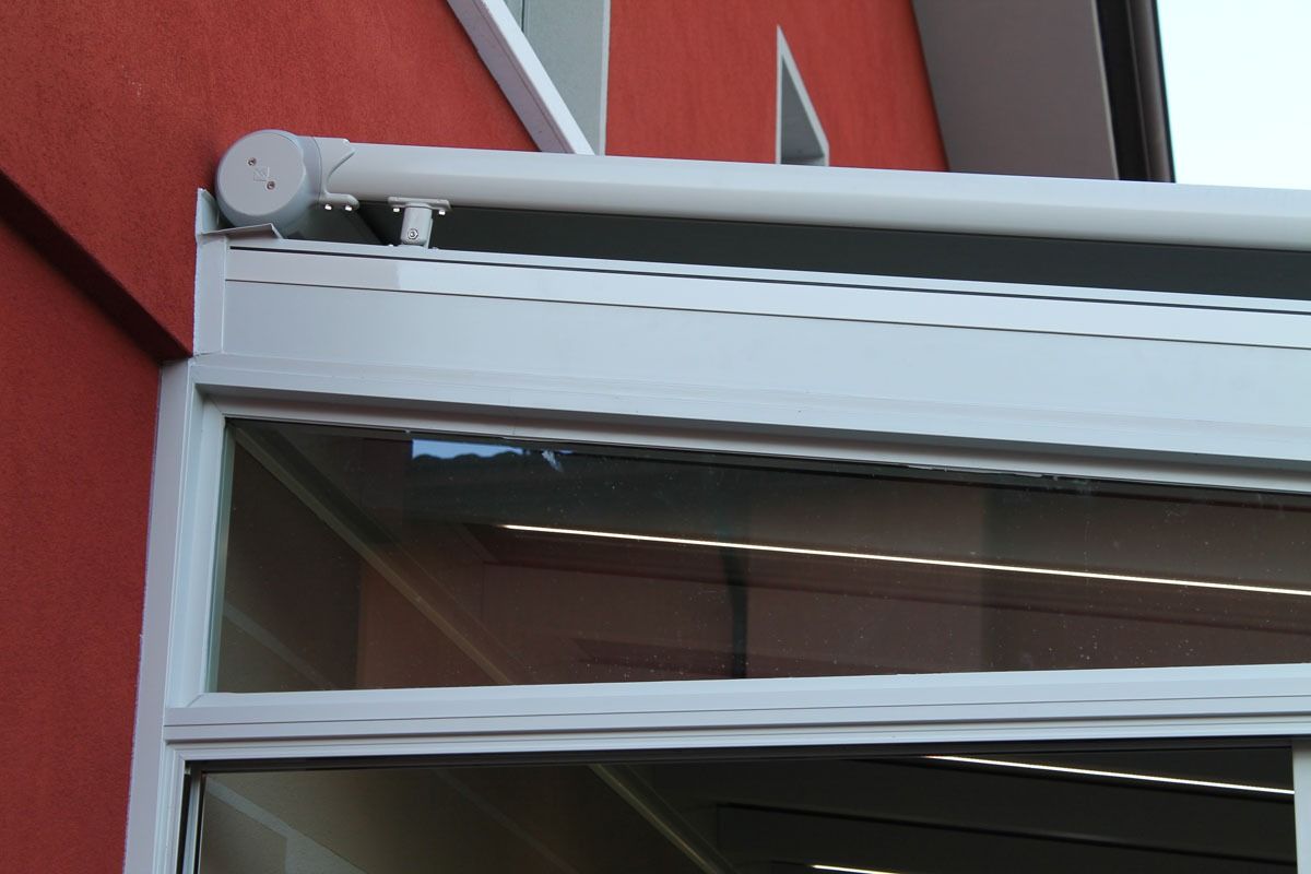 Tenda bianca fissata a un edificio rosso, con finestre in vetro.