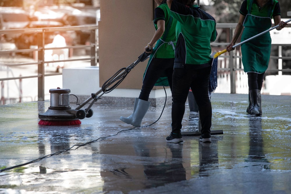 Man using a pressure washer to cleani the brick walkway of a house, removing dirt and grime efficiently.