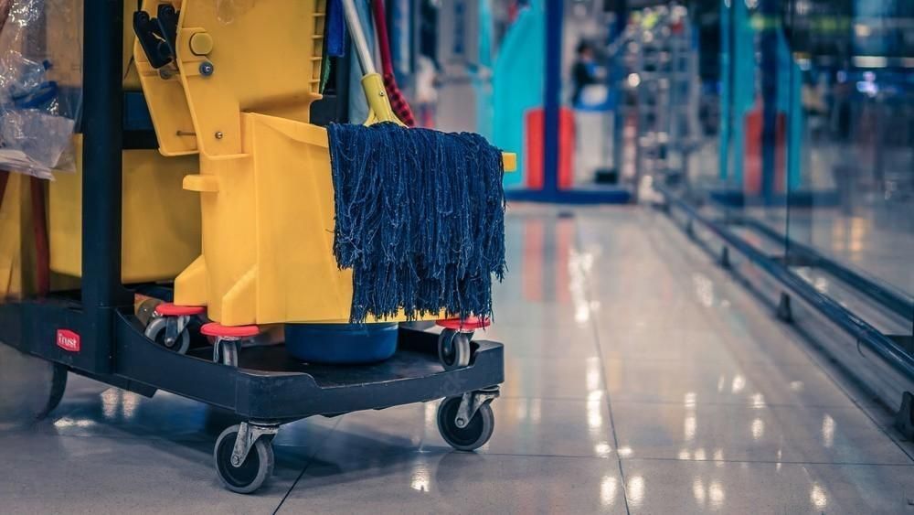 A mop is sitting on top of a yellow cleaning cart.