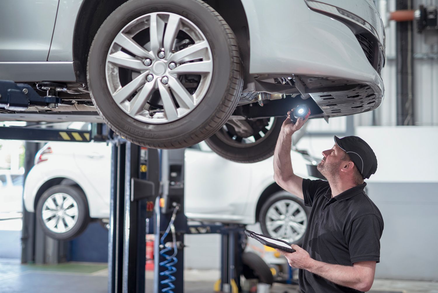 Automotive technician inspecting the vehicle transmission system on a car lift.