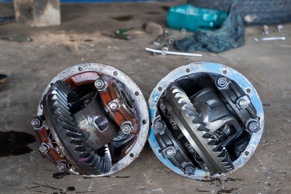 Two open differential housings on a garage floor, showing internal gears.