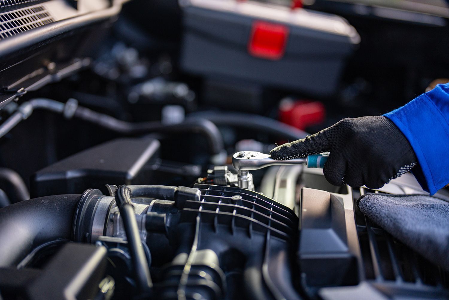 Automotive technician performing repair work on engine components.
