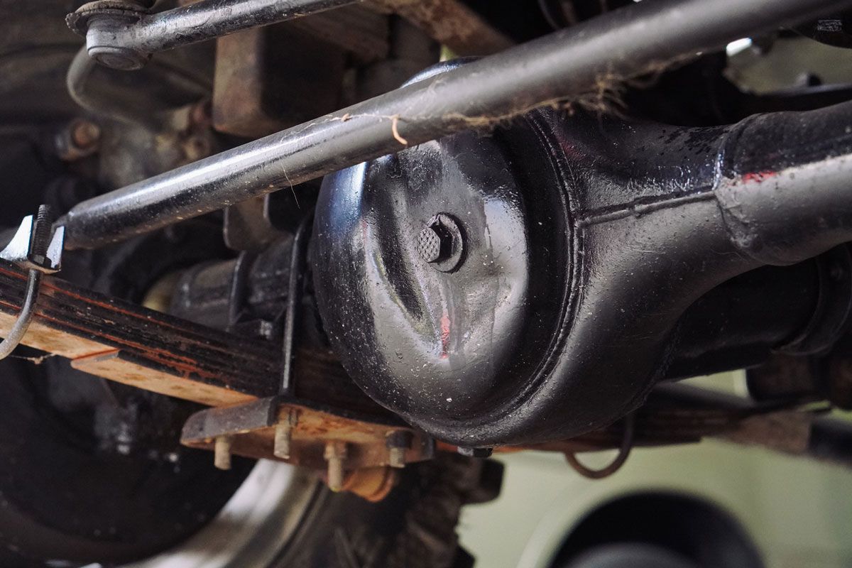 Black painted car axle, visible leaf spring, and steering components.