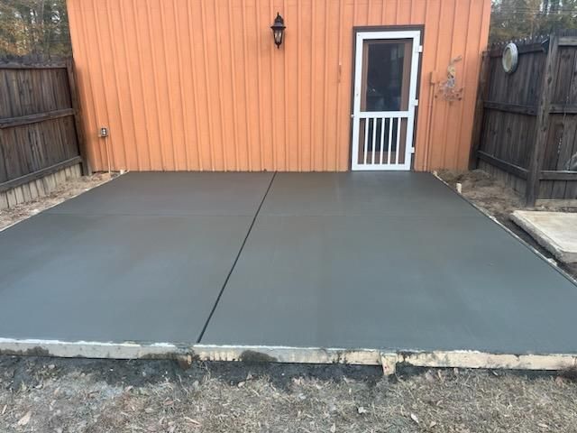 A concrete patio in front of a house with a screen door.