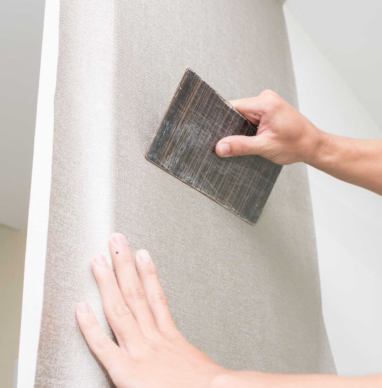 A person is sanding a wall with a sander.