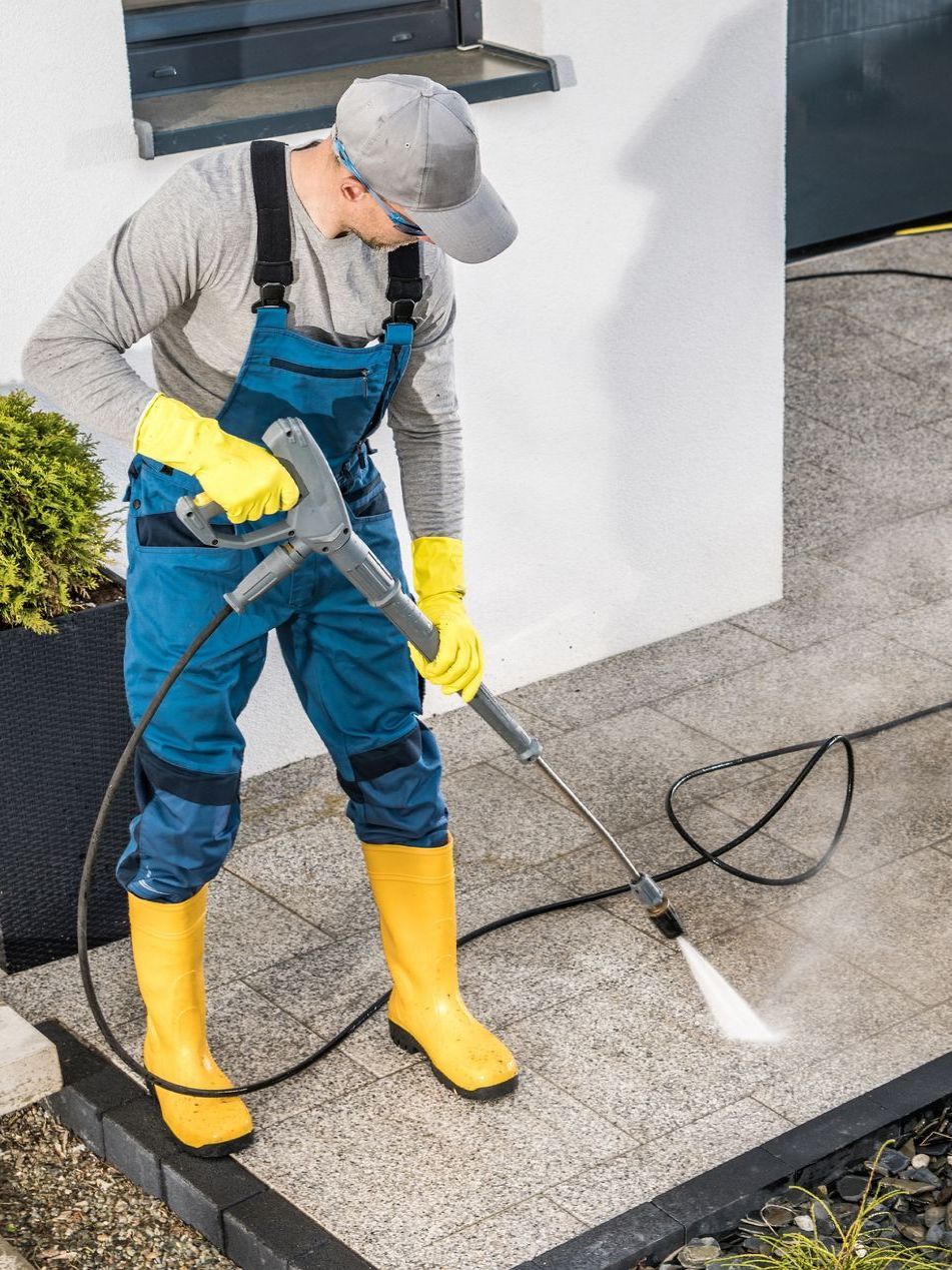 A man is cleaning a patio with a high pressure washer.