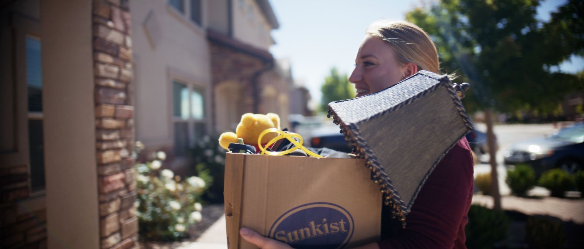 Person carrying a cardboard box labeled 