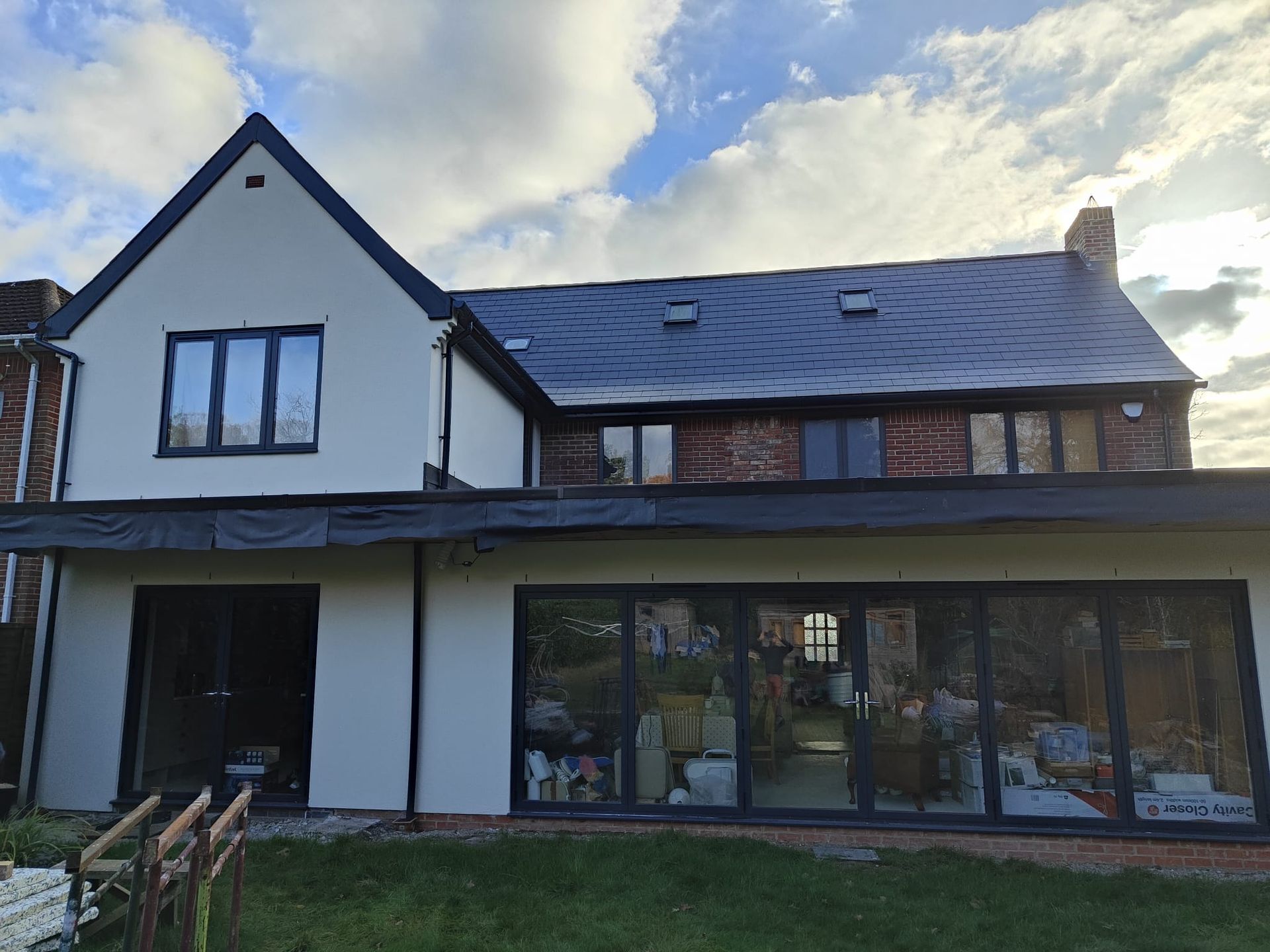 A large white house with a black roof and a lot of windows and external insulation.