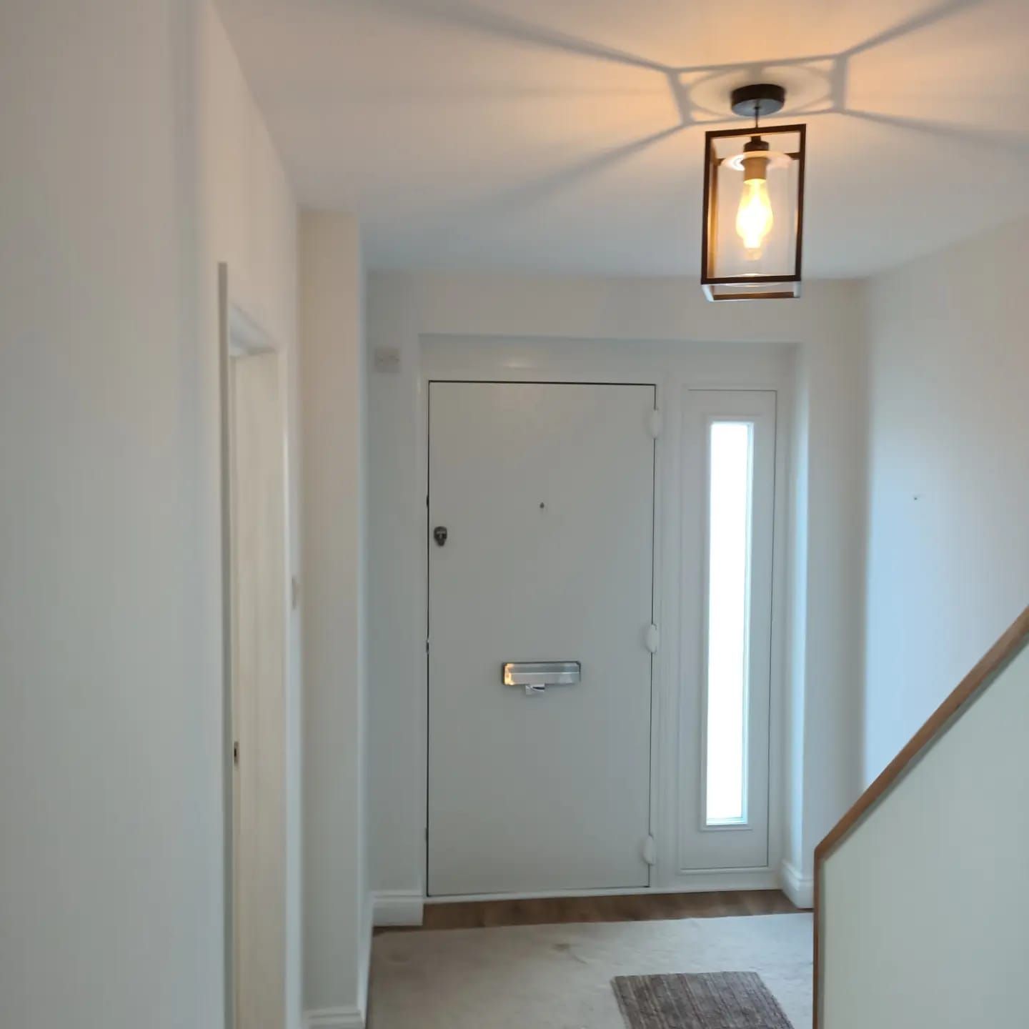 A hallway with a white door and a light on the ceiling