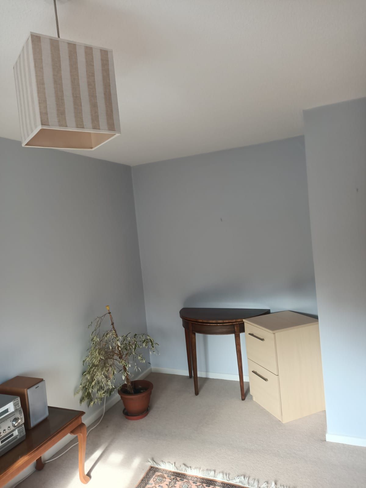 A living room with a striped lamp hanging from the ceiling