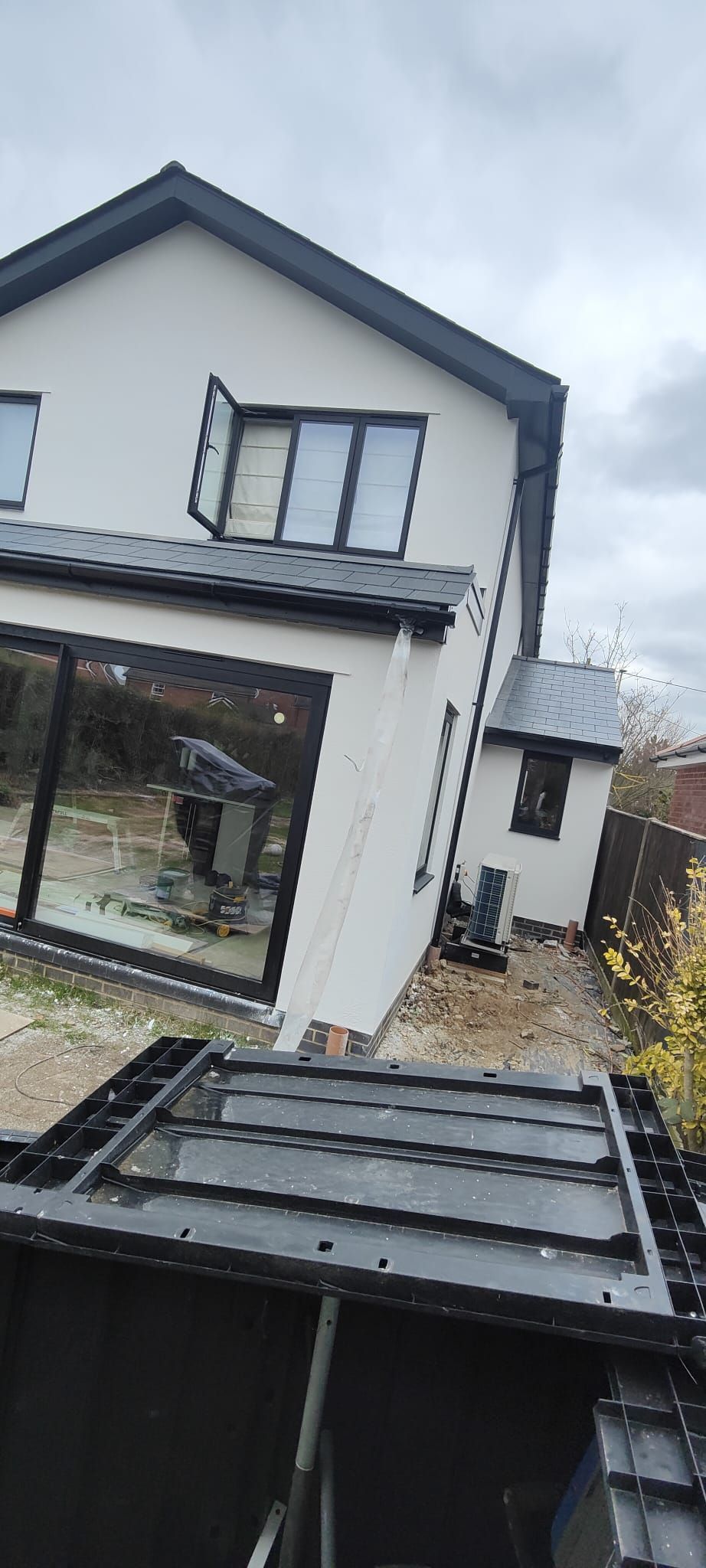 A white house with a black roof and a lot of windows and external rendering and insulation