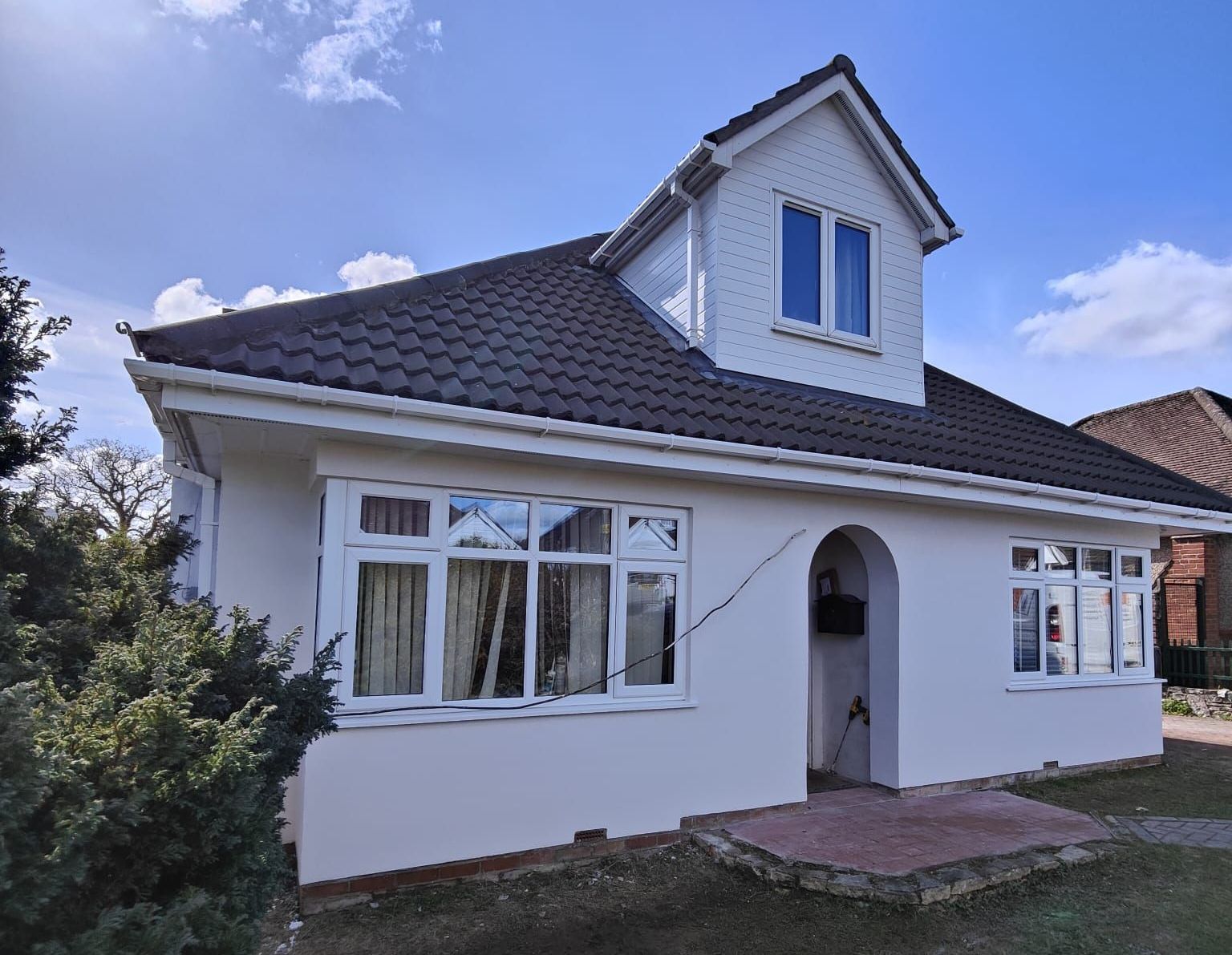 A white house with a black roof and external insulation