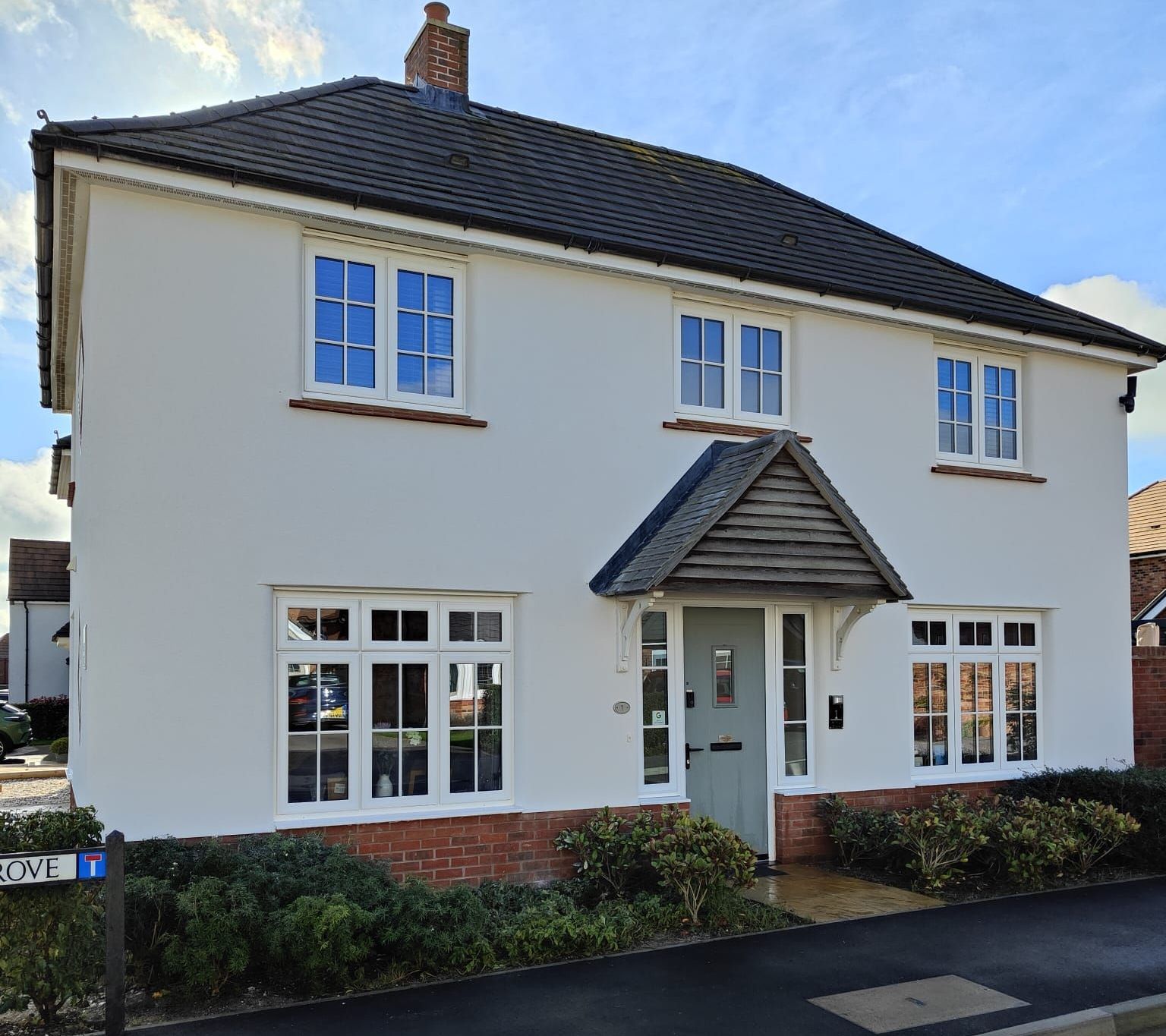 A white house with a black roof and blue windows