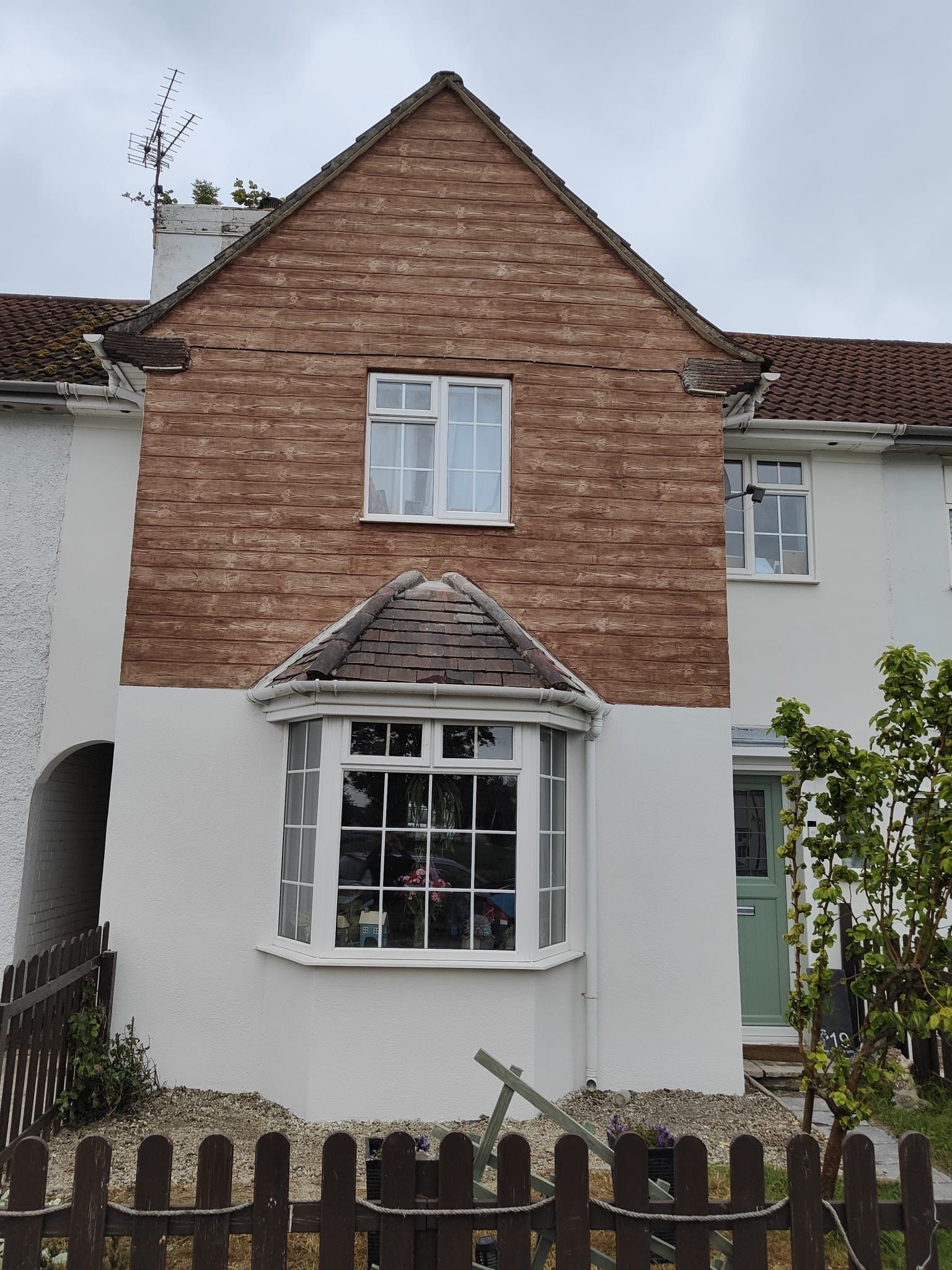 A white house with a brick facade and a wooden fence