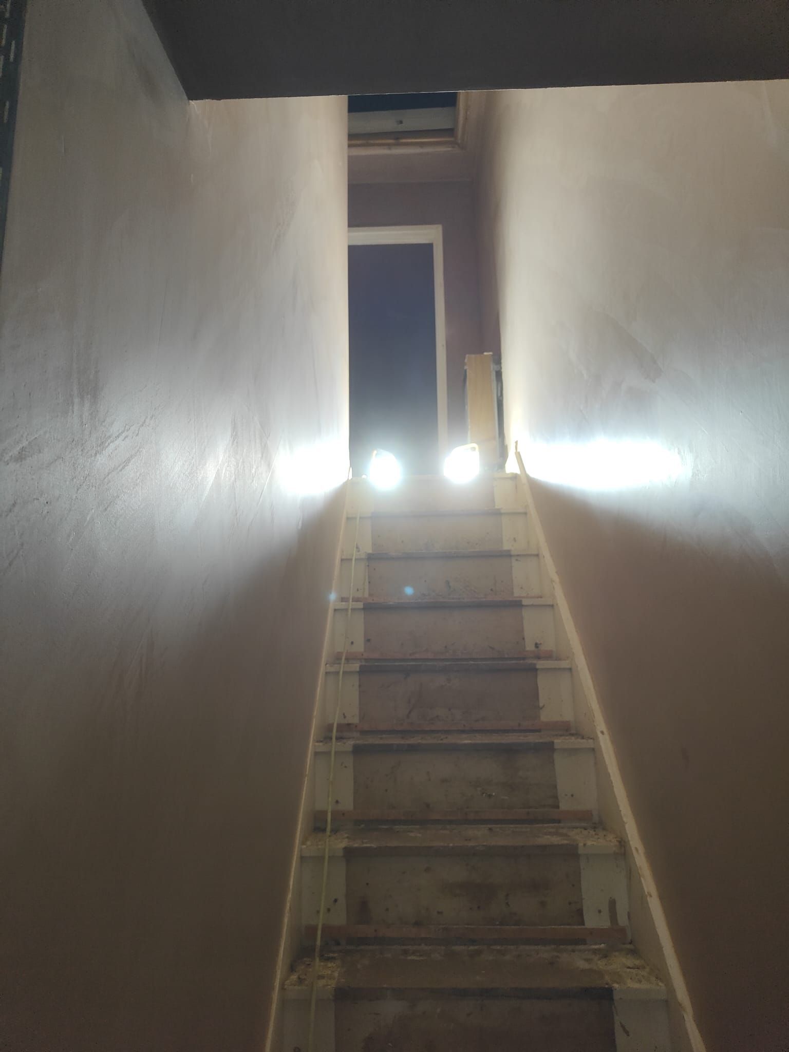 A dark hallway with stairs leading up to a door.