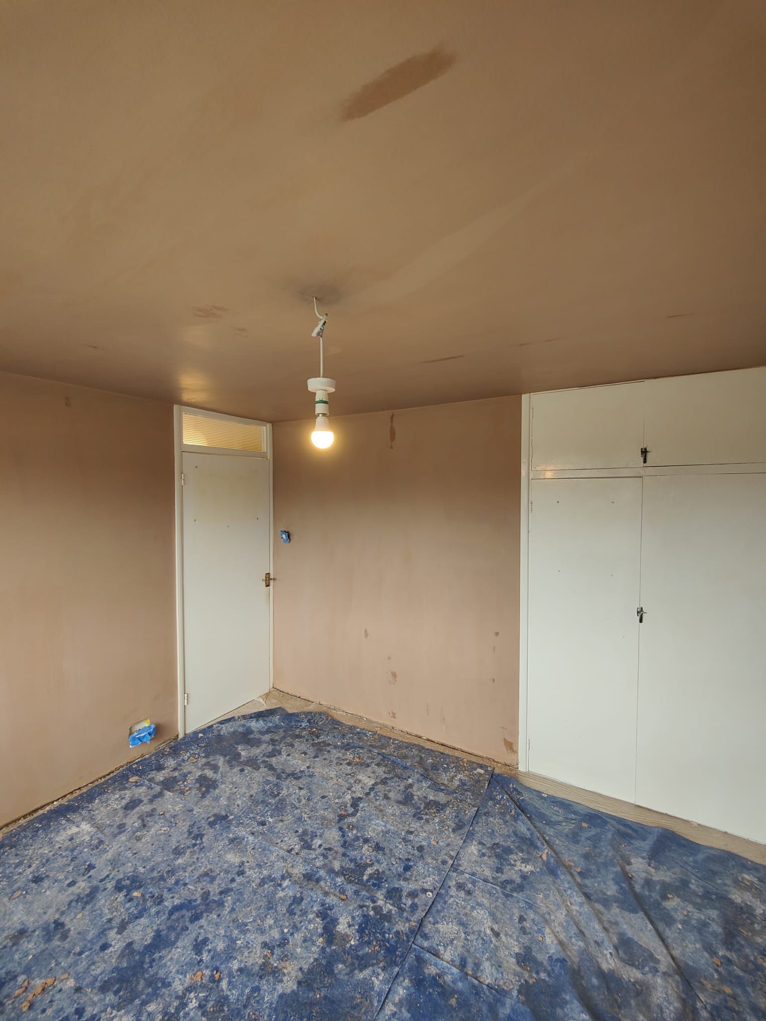 An empty room with a blue carpet and a light on the ceiling.