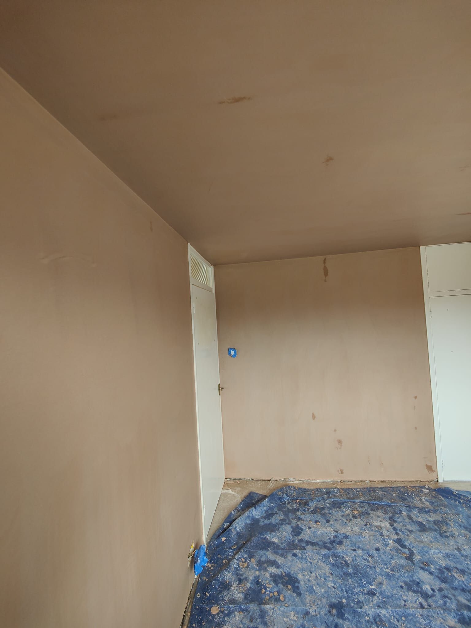 A room with a blue tarp on the floor and a ceiling.