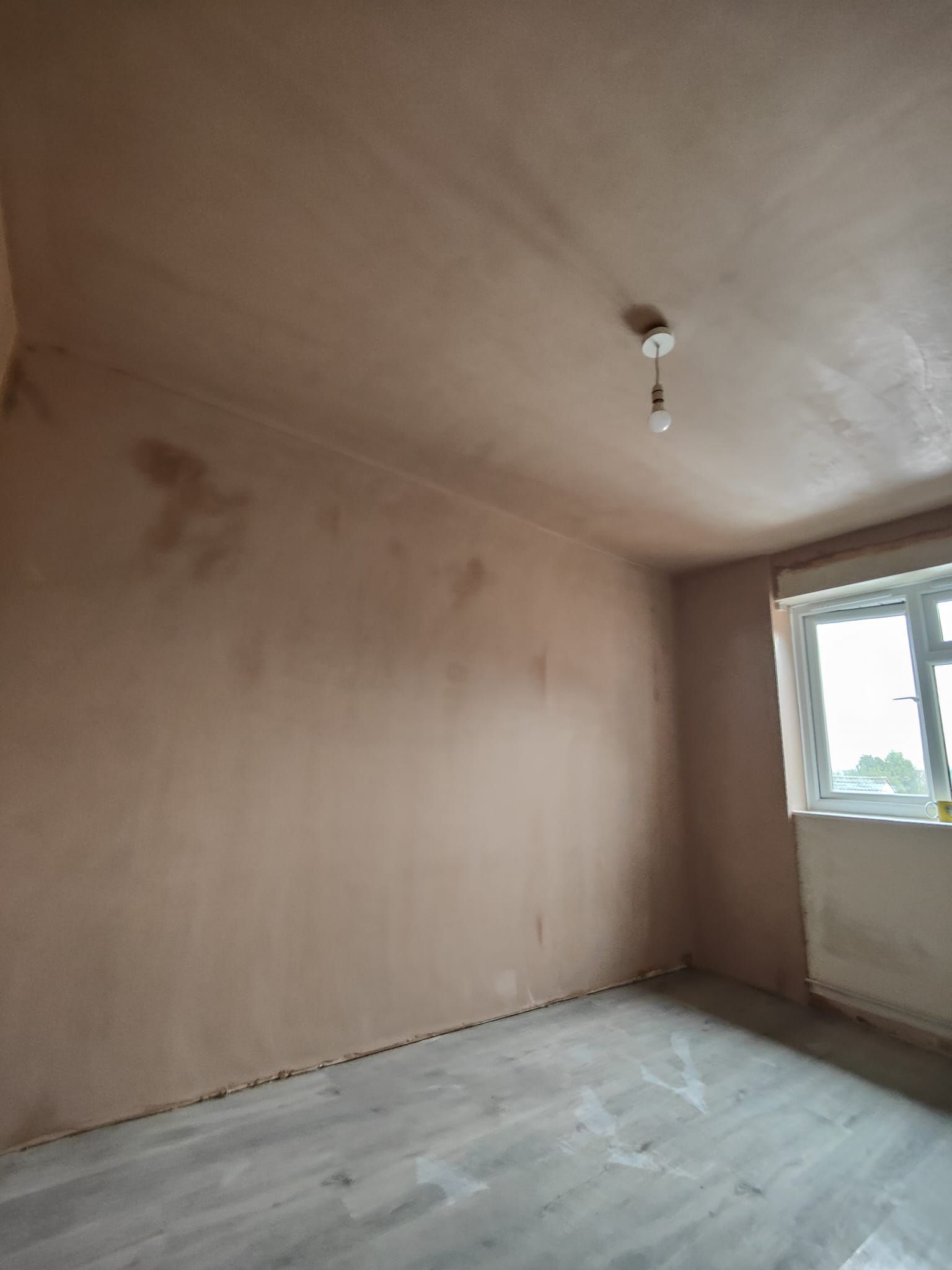 An empty room with a window and a light on the ceiling.