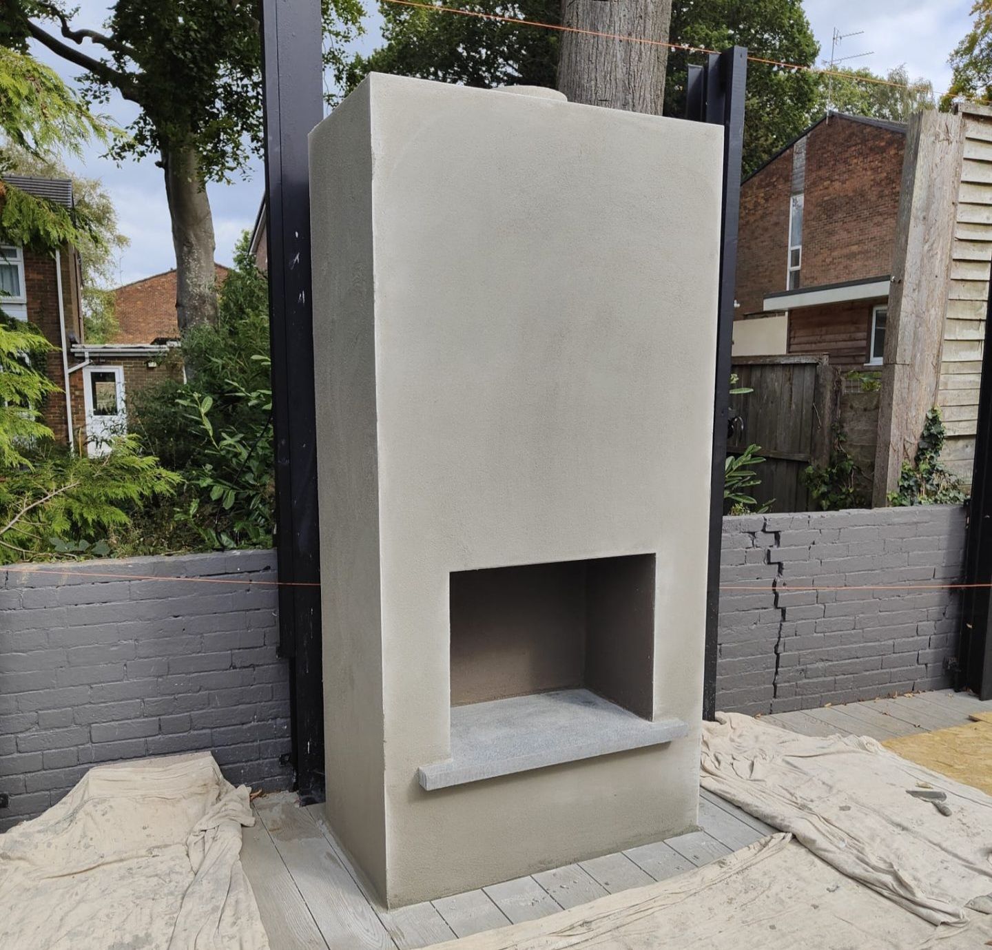 A concrete fireplace is being built in a backyard
