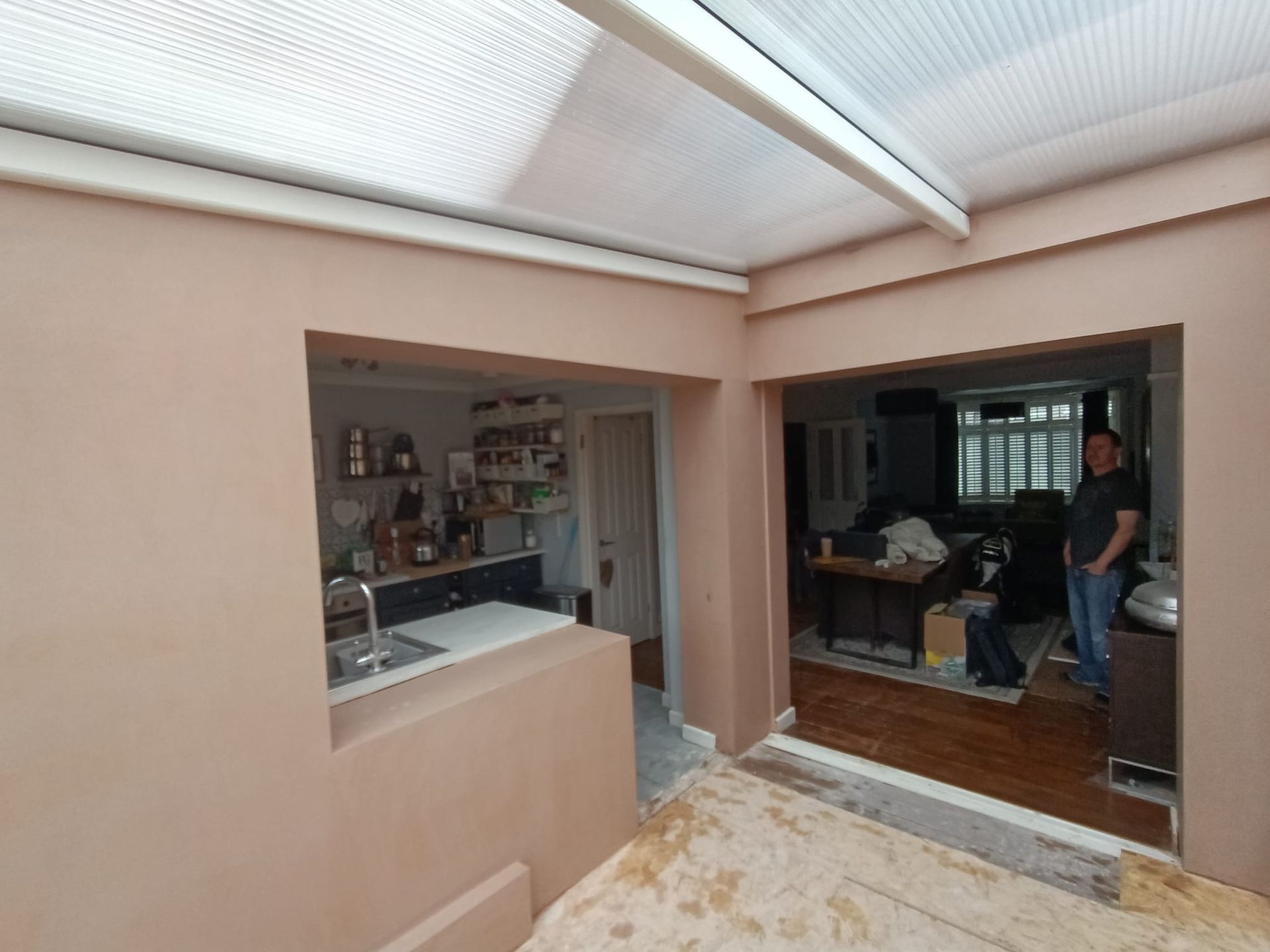 A man is standing in a kitchen next to a window.