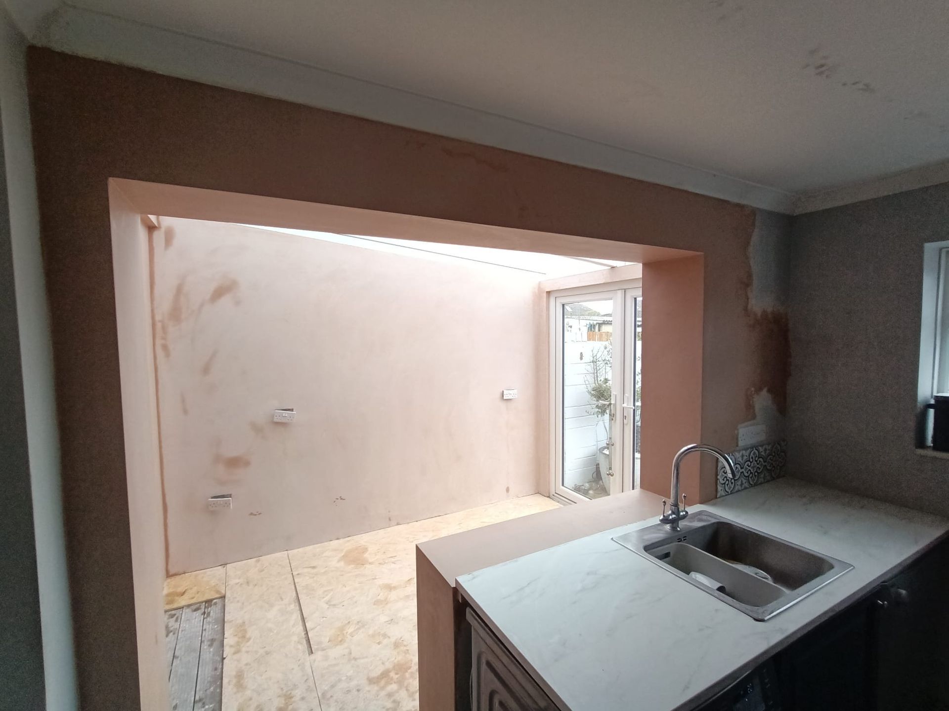 A kitchen with a sink and a sliding glass door.