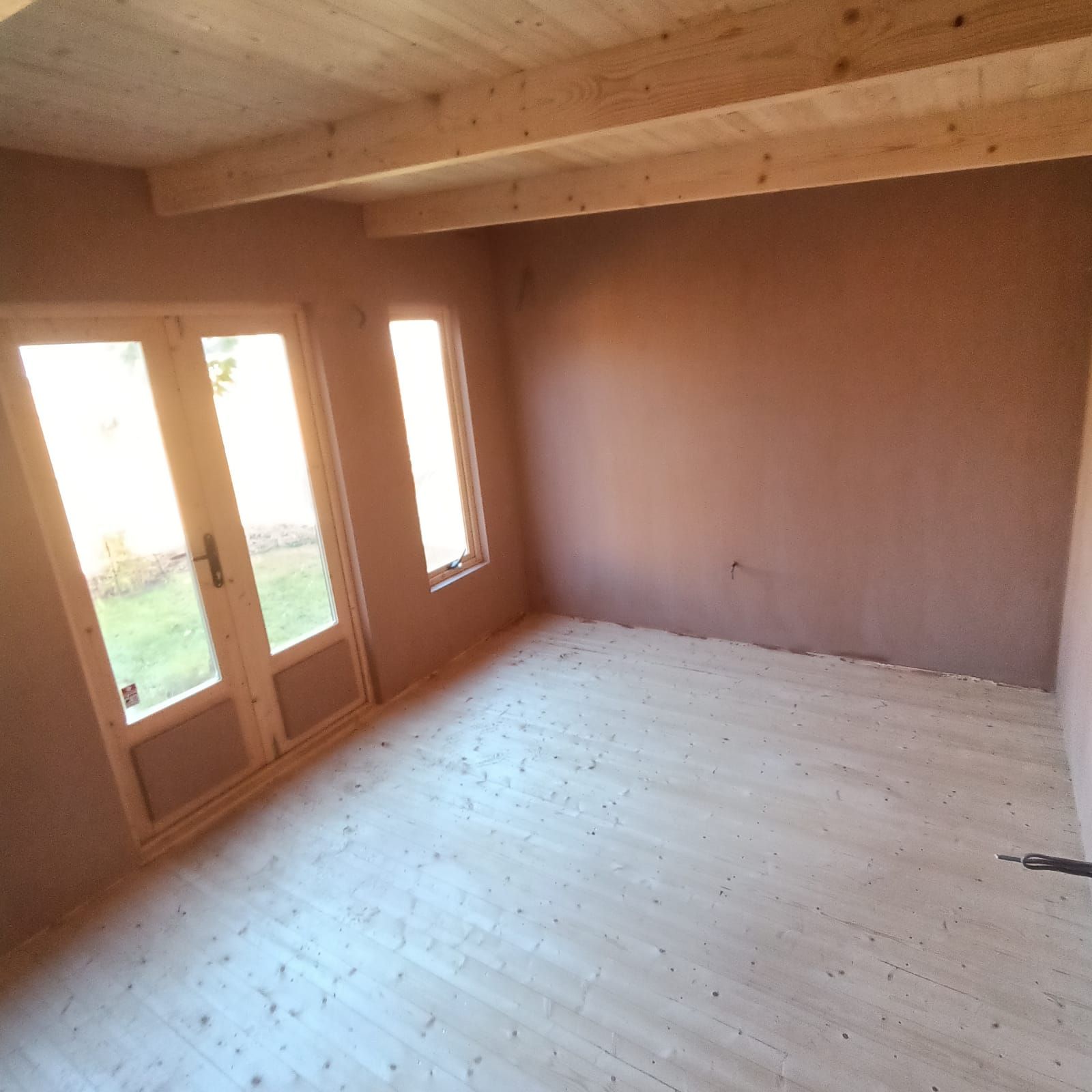 An empty room with wooden floors and windows