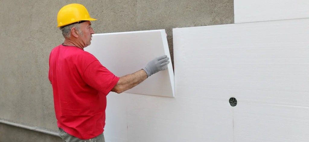 Construction worker installing external wall insulation boards on a house exterior