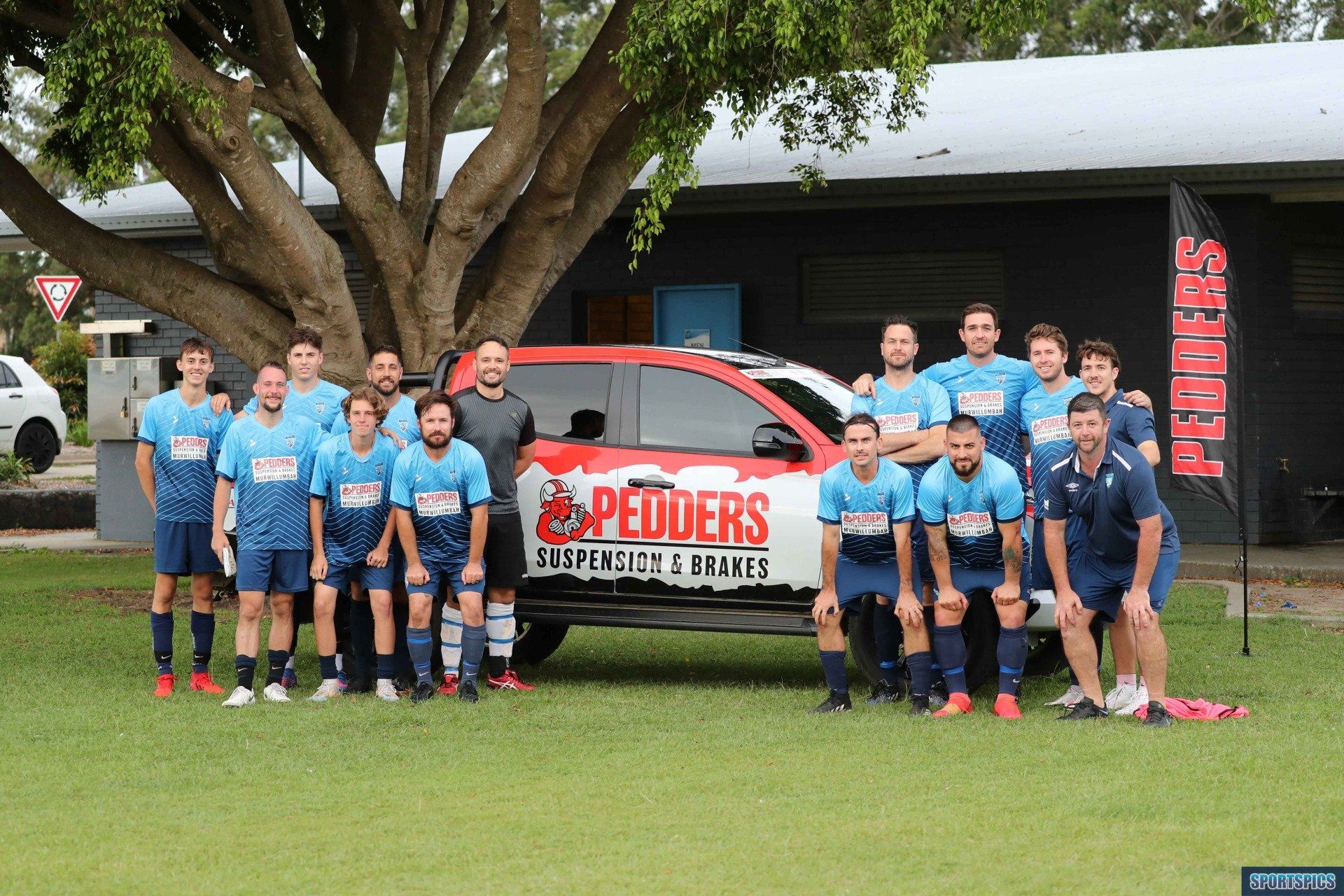 tweed united soccer team standing in front of a sponsor's vehicle