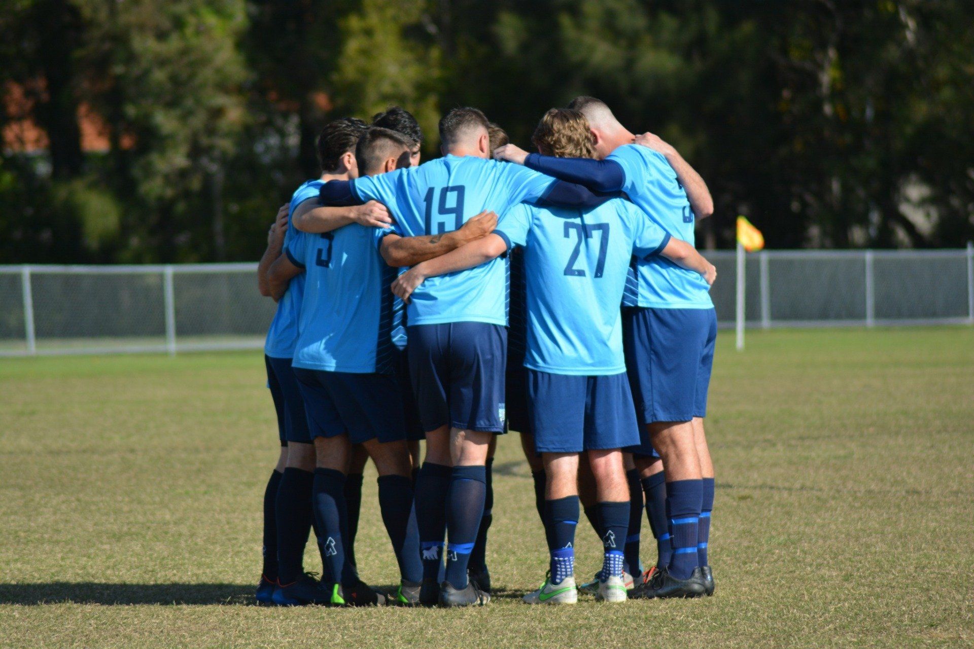 Tweed United soccer players in a huddle on the pitch