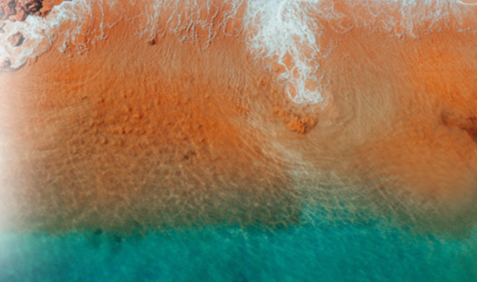 An aerial view of a sandy beach next to a body of water.