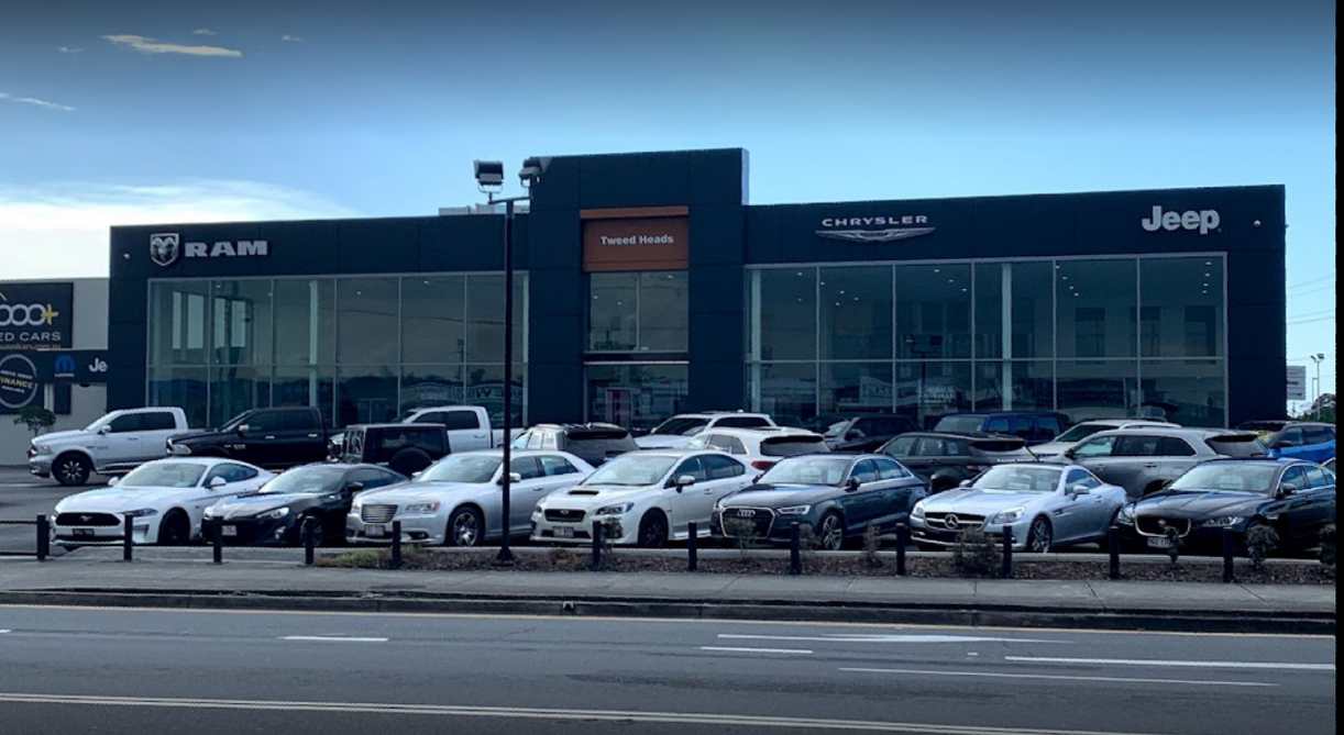 A jeep dealership with a lot of cars parked in front of it.