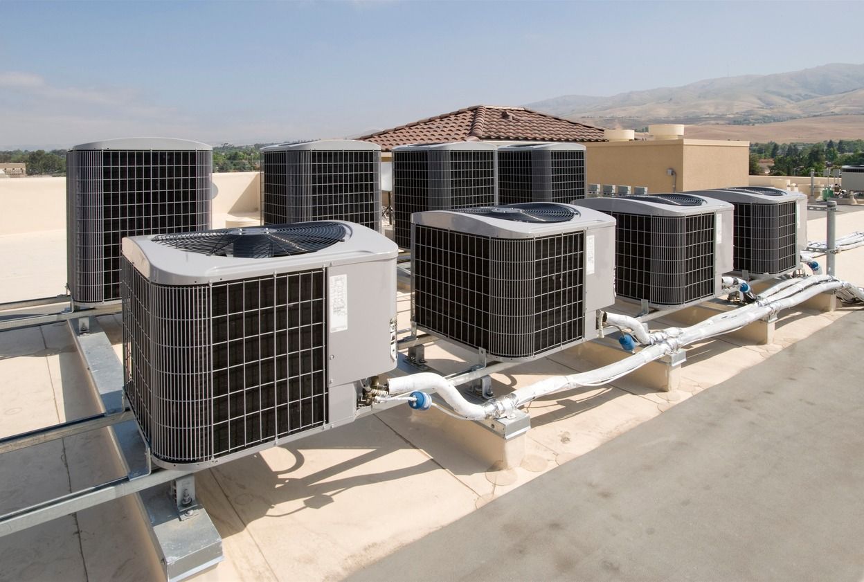 A row of air conditioners are sitting on top of a building.