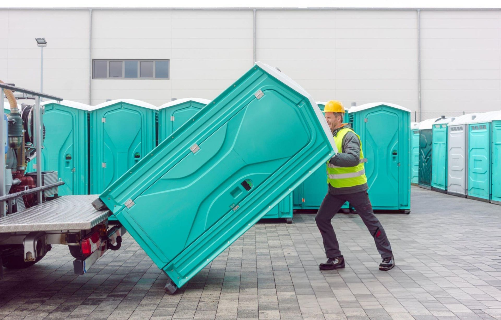 A man organizes and loads portable toilets in a warehouse for efficient portable toilet rental. A man organizes and loads portable toilets in a warehouse for efficient portable toilet rental.