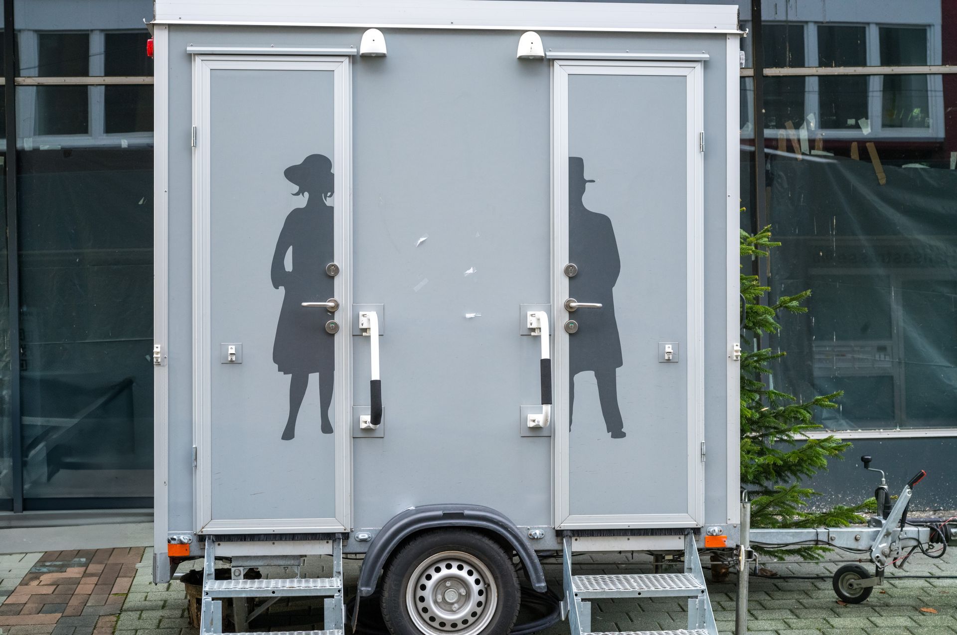 Portable restroom trailer with two private stalls, steps, and clear entry doors.