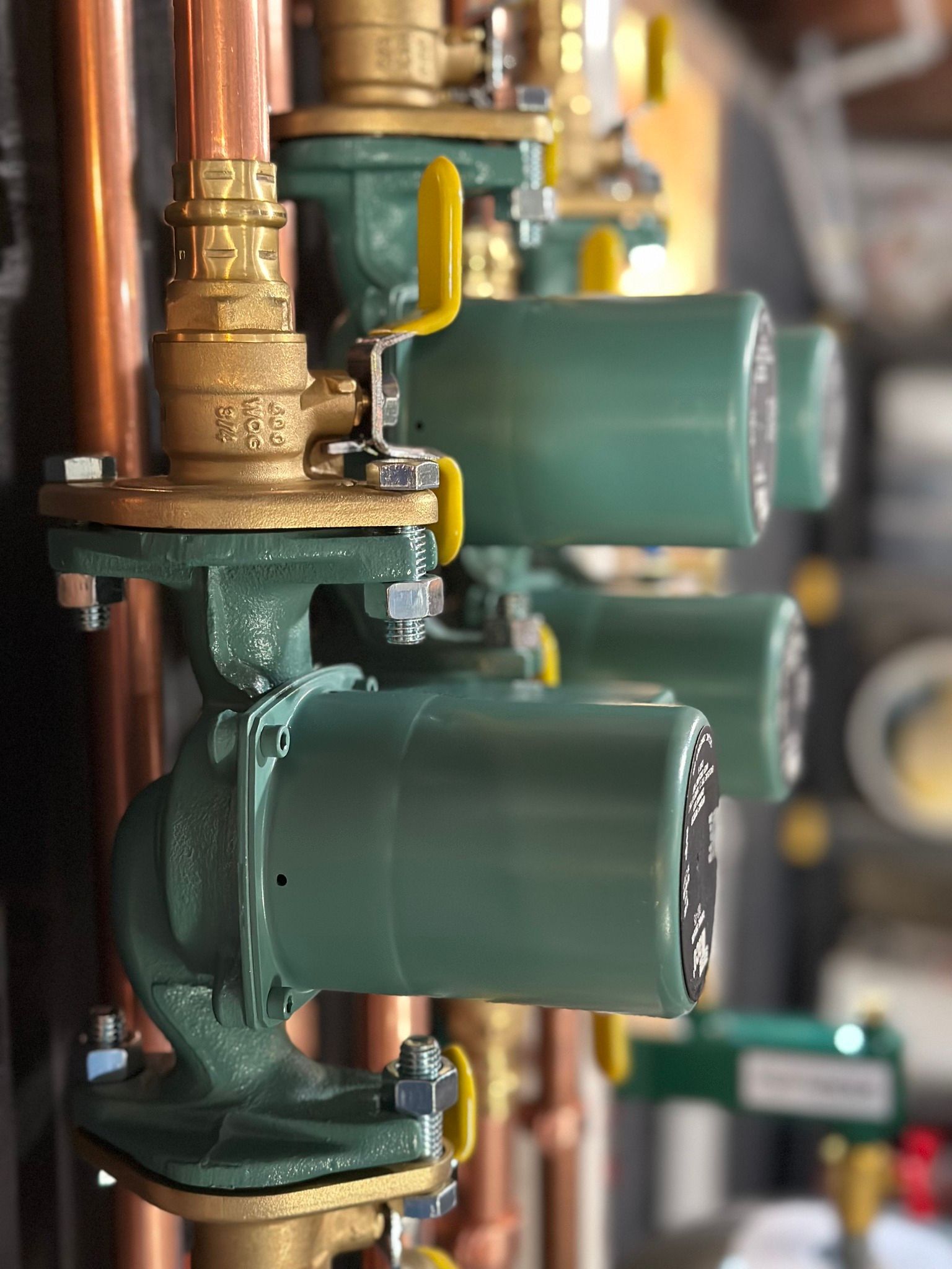 A row of green valves sitting on top of copper pipes.