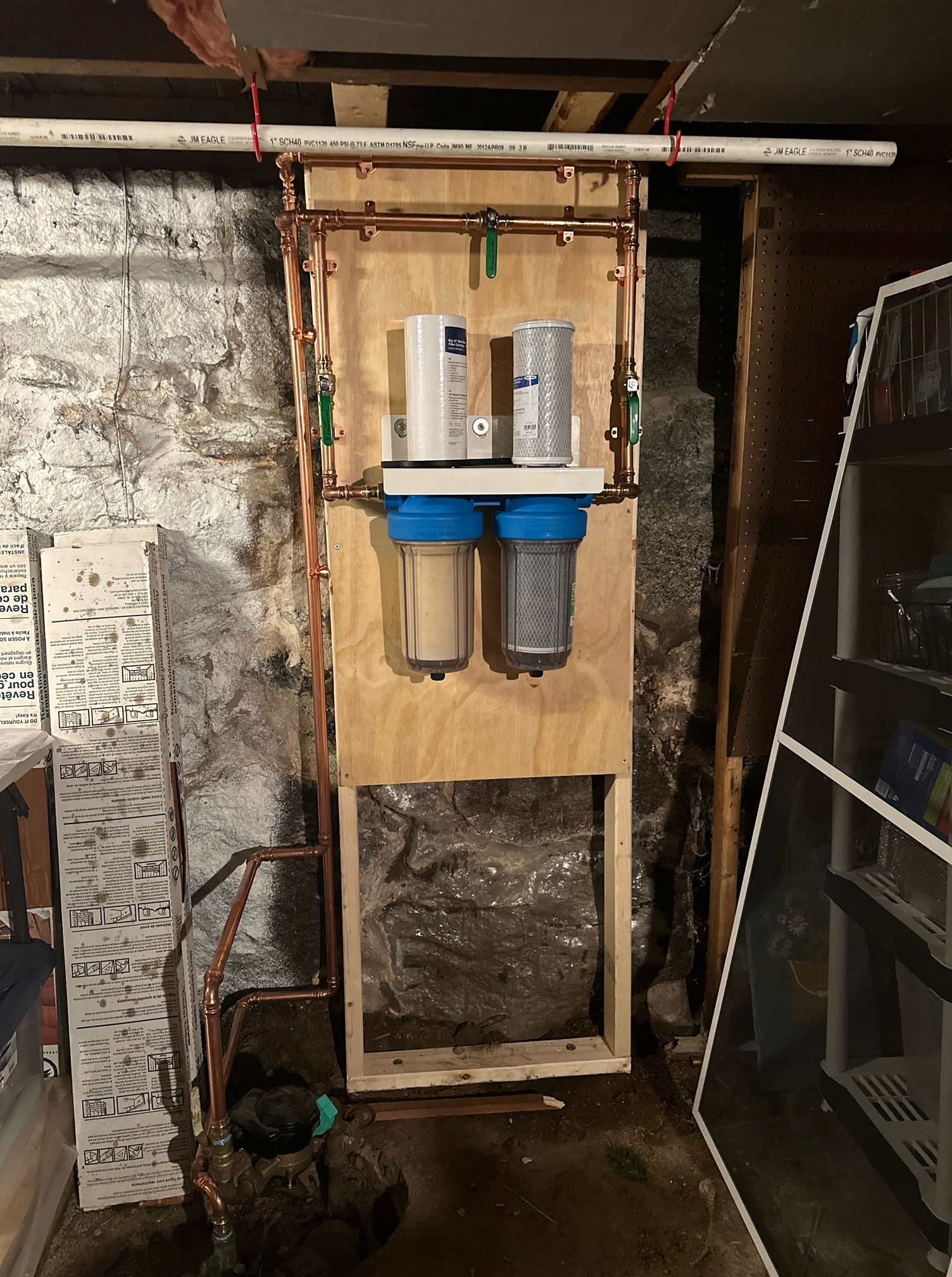 A water filter is mounted to a wall in a basement.