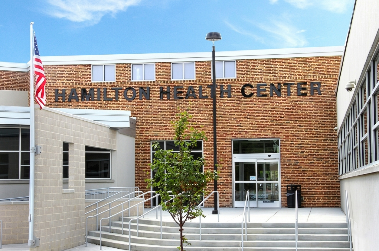 Exterior of a brick community center with U.S. flag, ramp, and entrance doors