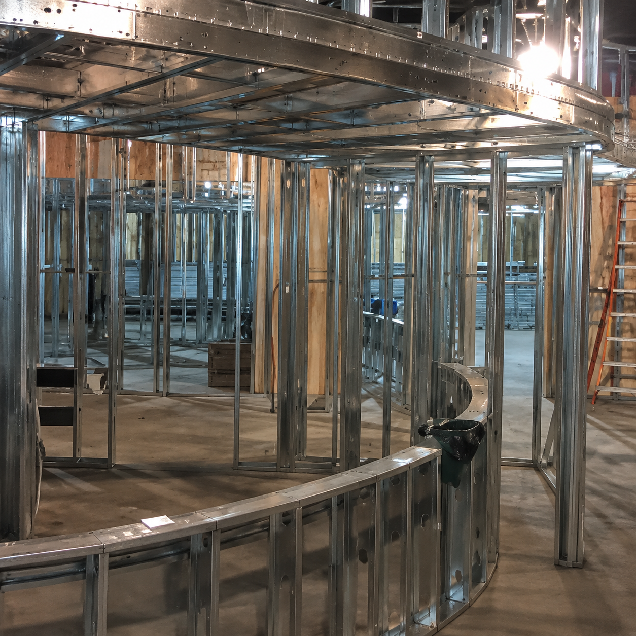 Shiny metal framework with curved supports inside an unfinished indoor construction space