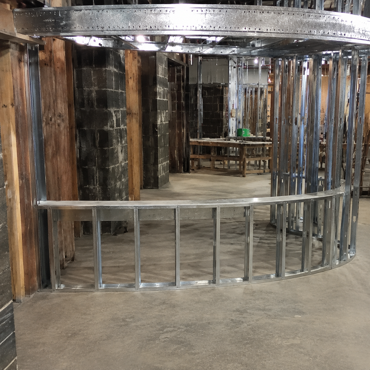 Shiny metal-framed mirrored structure in an indoor warehouse or workshop space.