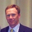 Headshot of a man in a suit and tie against a dark background