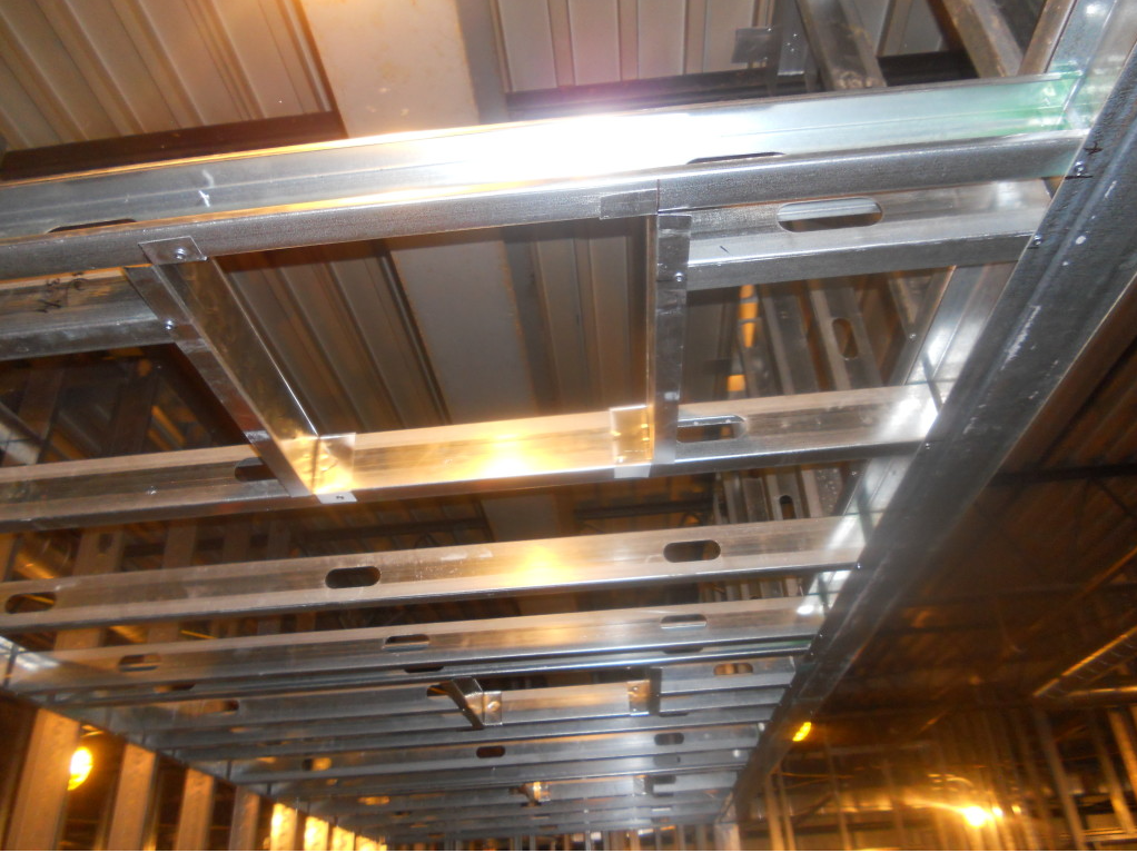 Metal ceiling beams and bright lights in an industrial walkway under construction