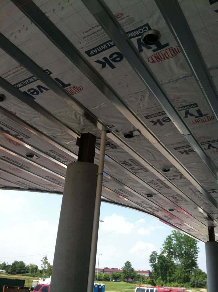 Underside of a roof under construction, with insulation panels and a support column visible.