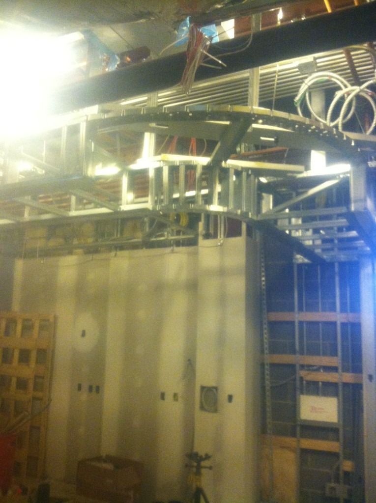 Industrial equipment in a dim utility room, with large metal panels and overhead pipes