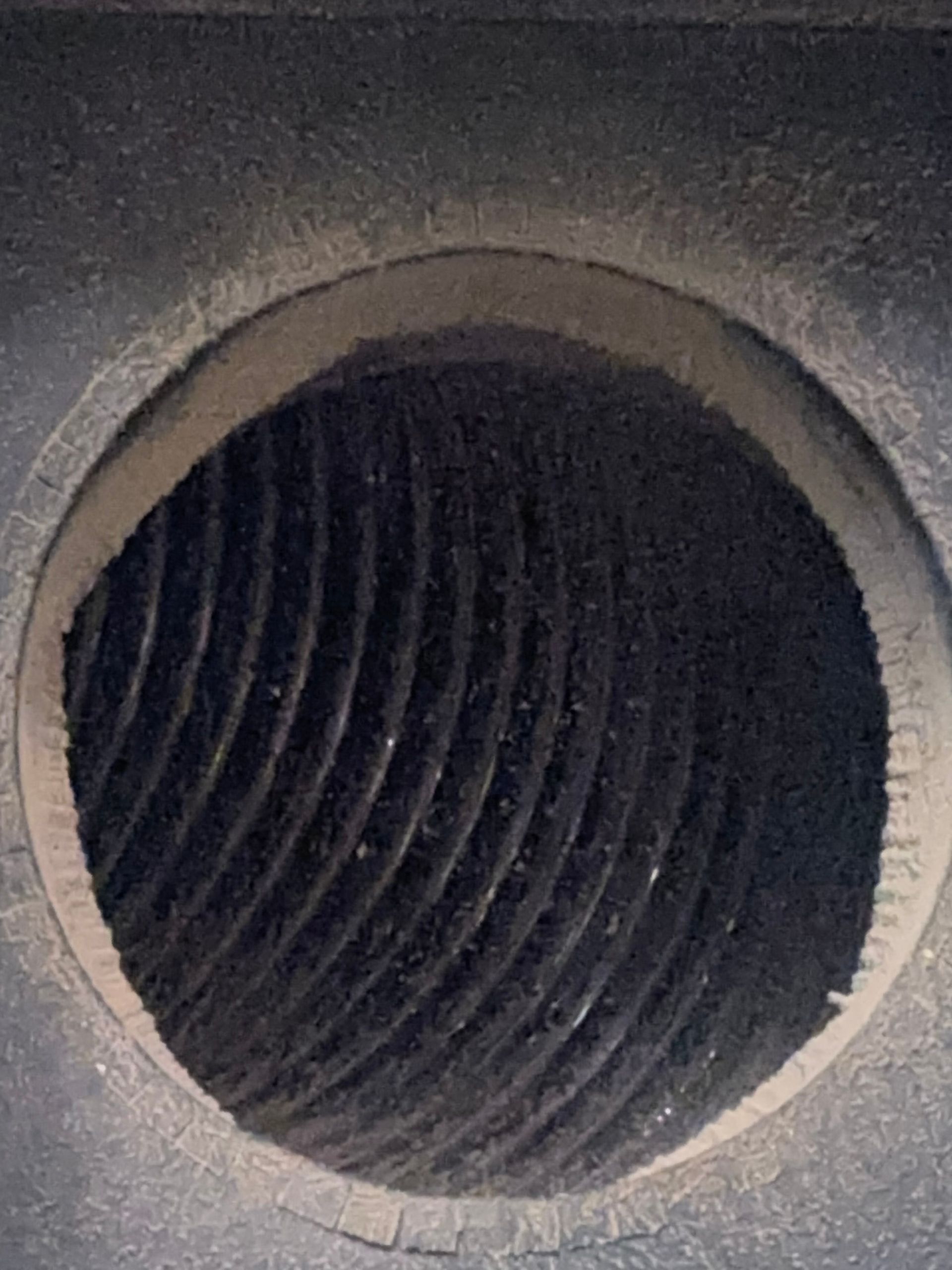 A close-up view of a dark, cylindrical chamber featuring internal circular grooves and textured, metal-like surfaces.