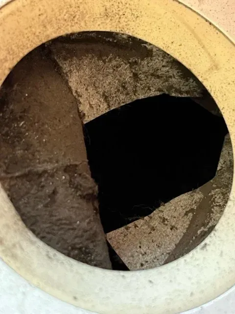 Looking down into a circular opening of a container with cracked, dark, textured interior panels.