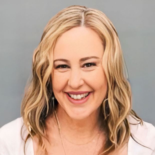 A woman with blonde hair and a white shirt is smiling for the camera.