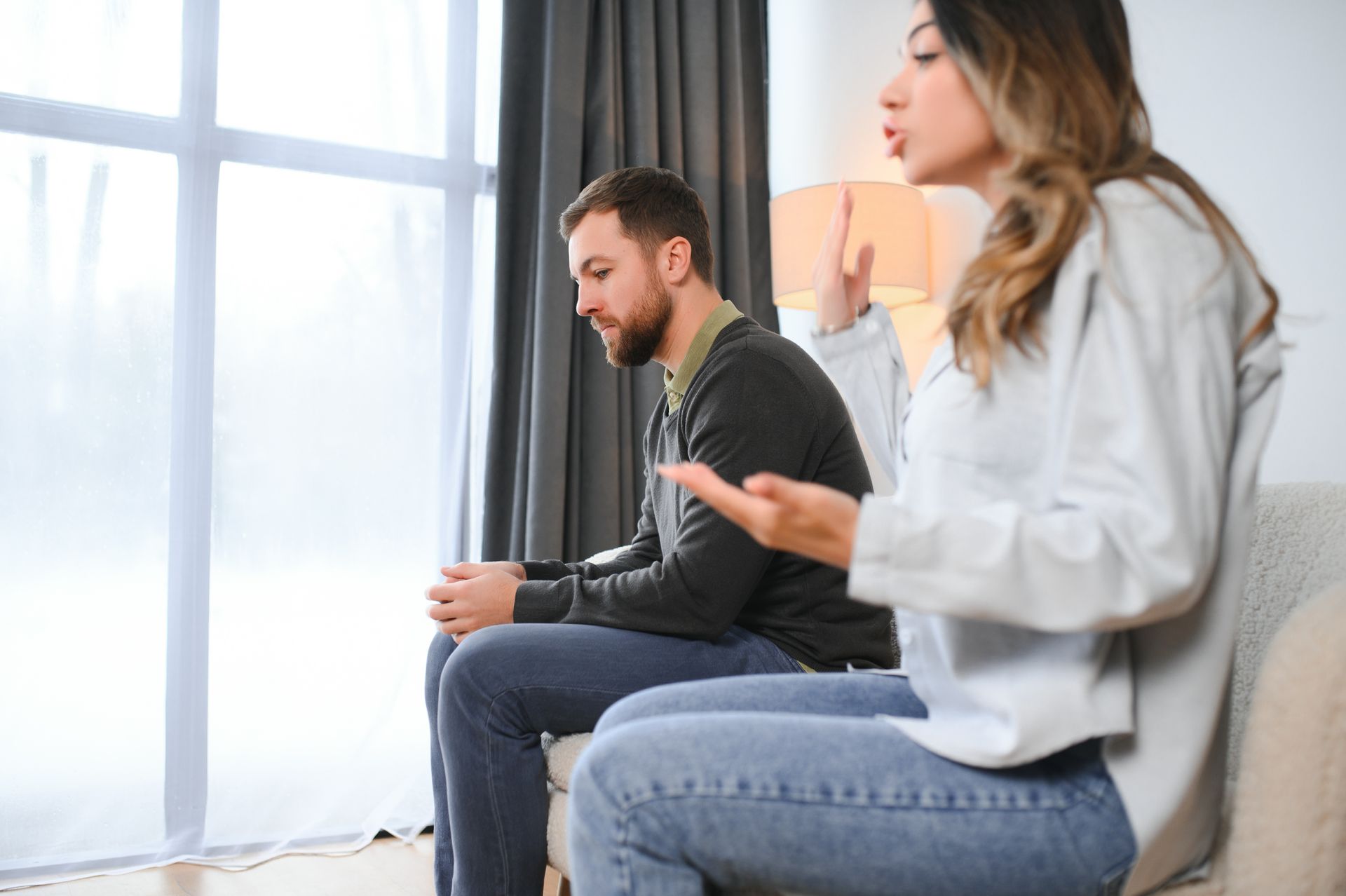 A man and a woman are sitting on a couch having an argument.