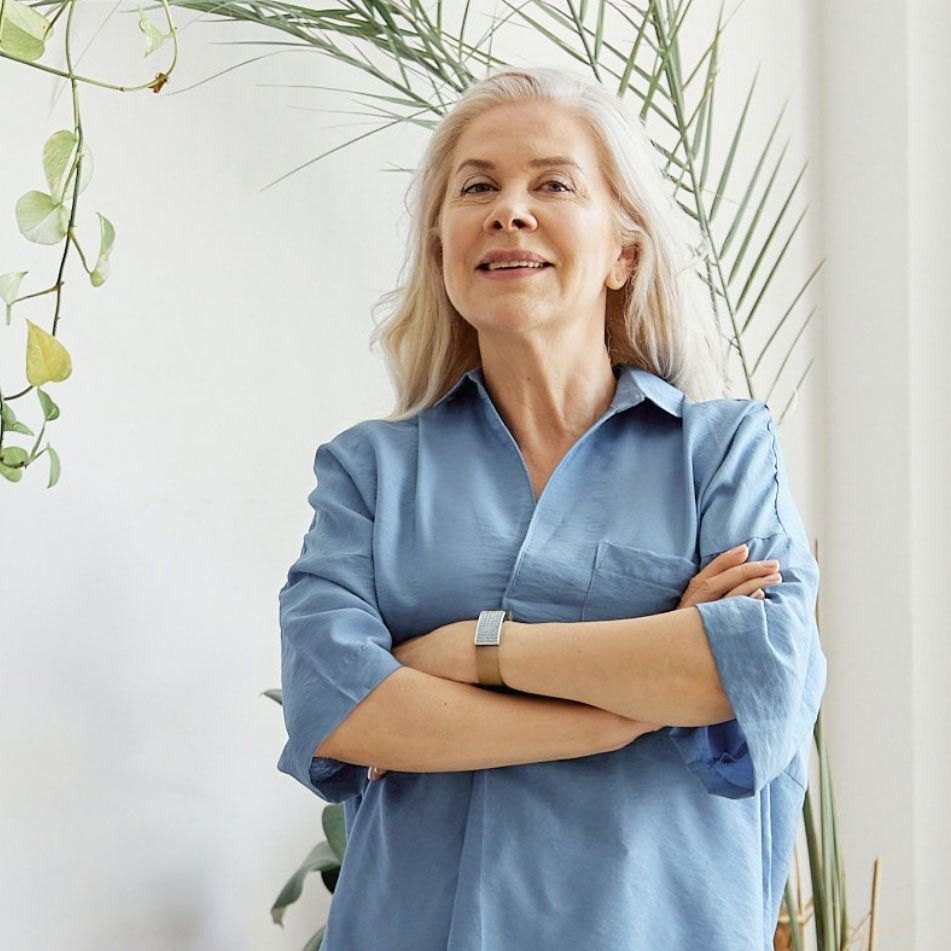 A woman in a blue shirt is standing with her arms crossed.