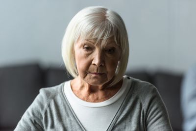 A woman wearing headphones is crying while listening to music.
