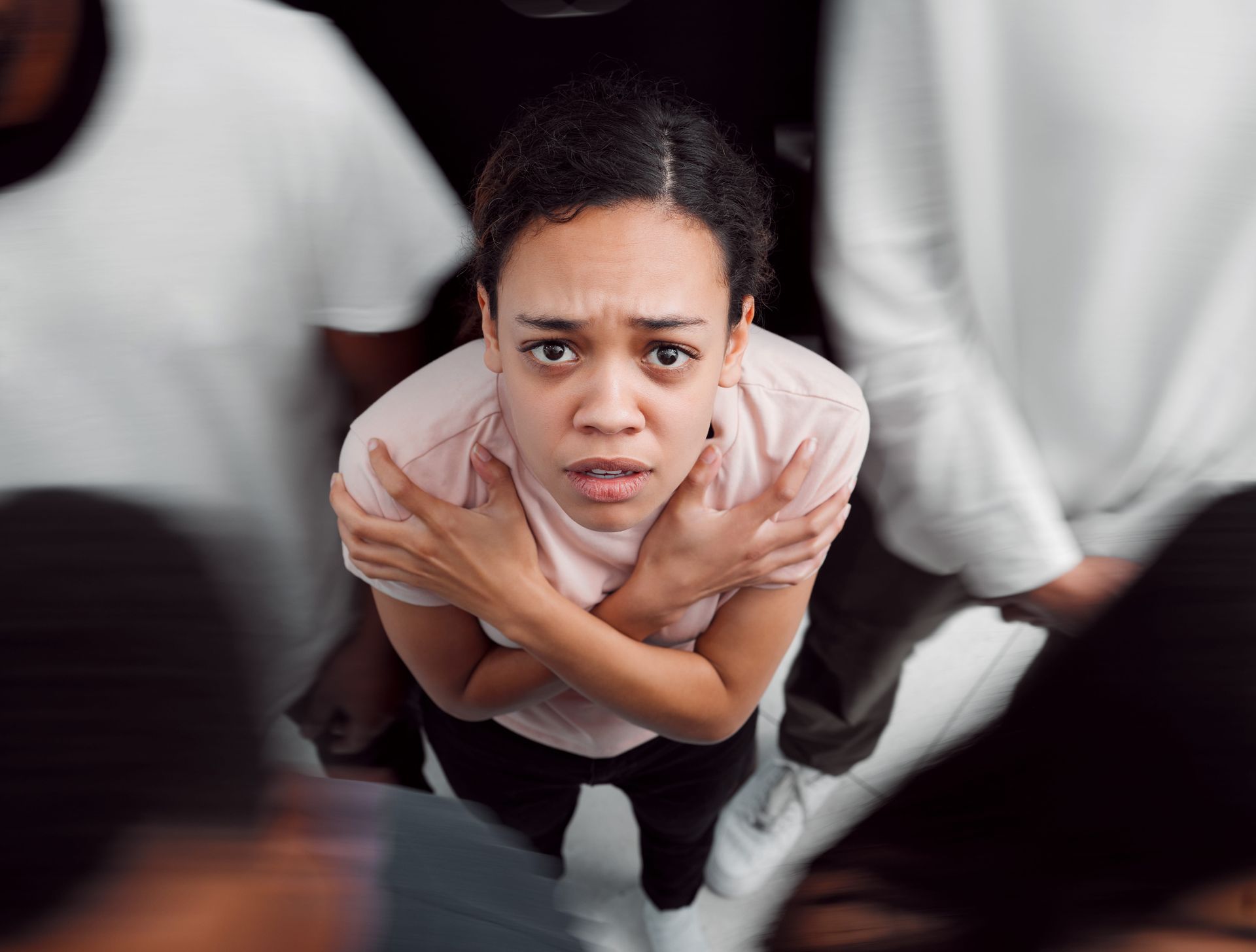 A woman is standing in a crowd of people with her arms around her chest.